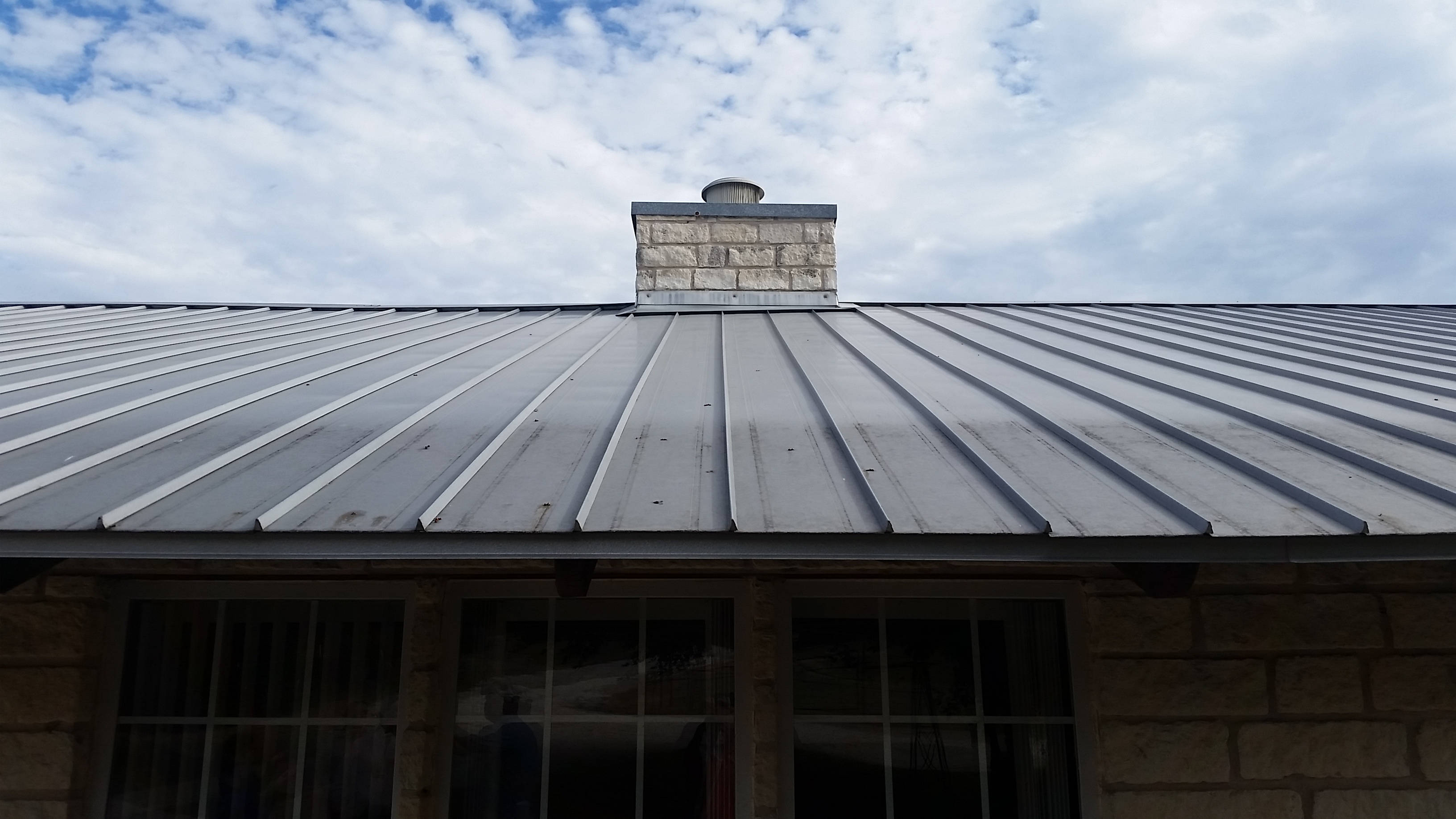 Standing seam metal roof on stone building with chimney — Heritage Roofing Stephenville TX