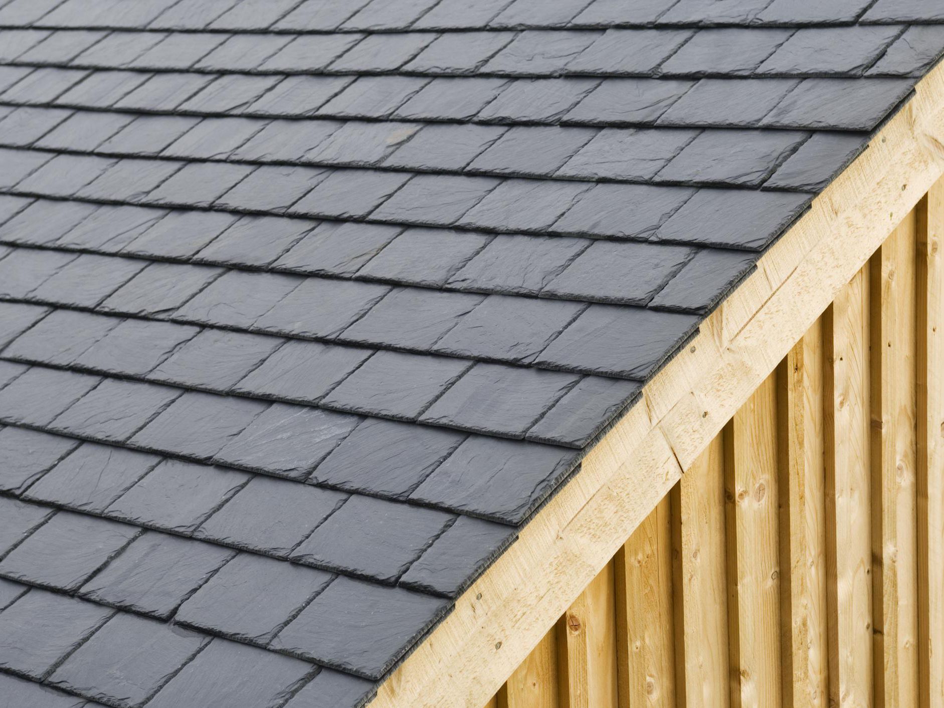 Natural dark slate tile roof with wood fascia — premium residential roofing material
