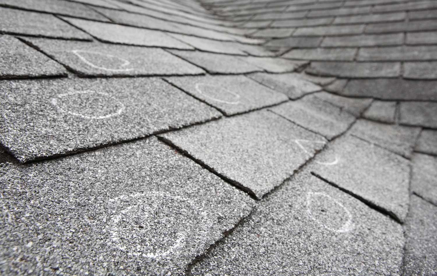 Chalk circles marking hail impact points on asphalt shingles at roof valley — Heritage Roofing storm damage inspection